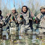 A group of men returning from hunting in winter with a full load.