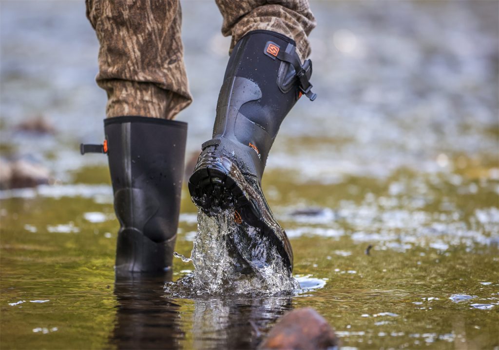 A man wearing HISEA boots is crossing a stream.