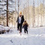 A mother is walking in the snow with her child, wearing HISEA boots.