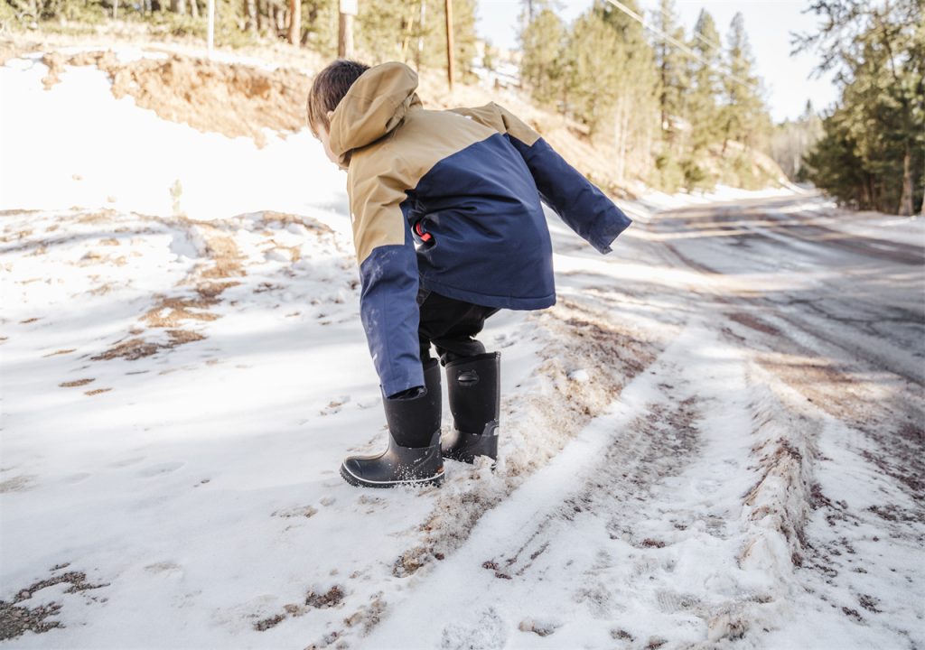 A little boy is walking on the snowy ground with HISEA snow boots.