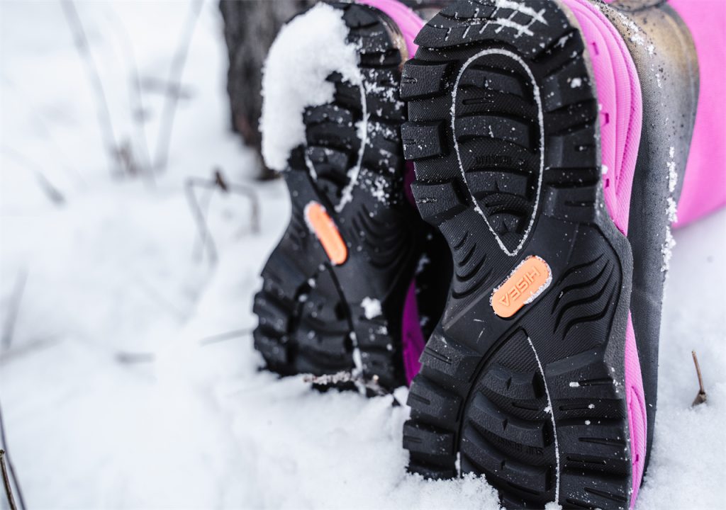 A woman is walking in the snow wearing HISEA snow boots.