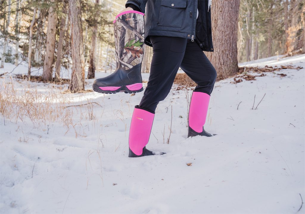 A woman is walking in the forest with HISEA snow boots, also holds a pair of camouflage snow boots in her hand.