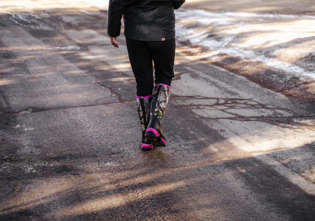 A woman in winter clothes walks on the road wearing HISEA snow boots.