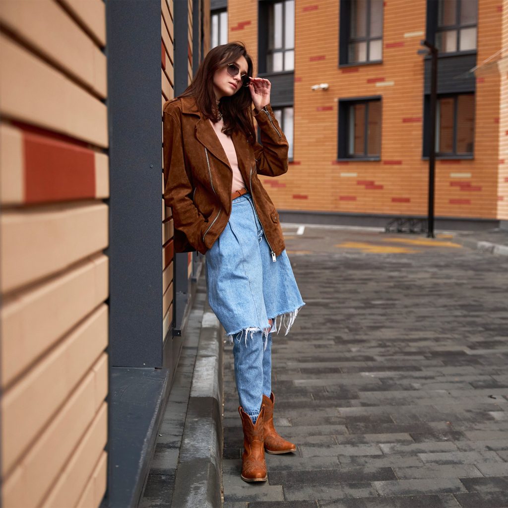 A model wearing sunglasses and frowning, wearing HISEA cowboy boots.